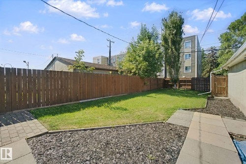 Expansive backyard featuring a privacy fence, established lawn, and a paved pathway - 12916 63 Street Nw, Edmonton, AB 