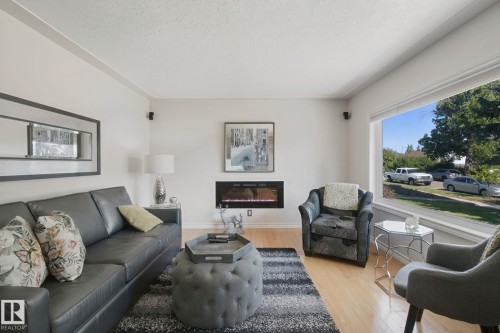 Light wood-finish flooring, built-in fireplace, and expansive window - 12916 63 Street Nw, Edmonton, AB 