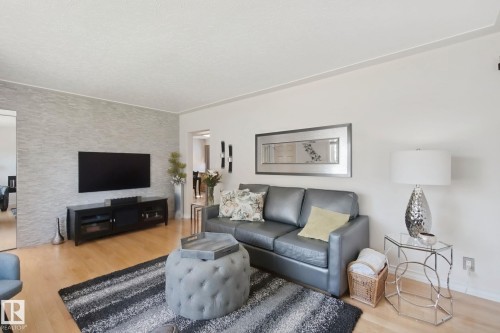 Light wood-finish flooring, accent wall with stacked stone, recessed wall mirror, and built-in wall sconces - 12916 63 Street Nw, Edmonton, AB 