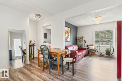 Open-concept living area featuring wood-finish flooring, white walls, and a prominent window with natural light - 12150 47 Street Nw, Edmonton, AB - Indoor Photo Showing Living Room