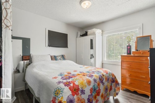 Bedroom featuring wood-finish flooring, a window with blinds, and white walls - 12150 47 Street Nw, Edmonton, AB - Indoor Photo Showing Bedroom