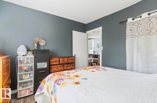 Spacious bedroom featuring wood-finish flooring and a neutral color palette - 12150 47 Street Nw, Edmonton, AB - Indoor Photo Showing Bedroom
