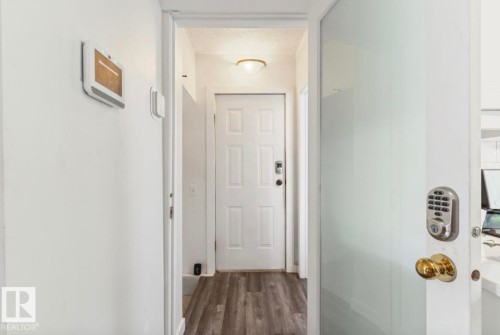 Entryway featuring wood-finish flooring, a white paneled door with a digital keypad lock, and a flush mount ceiling light - 12150 47 Street Nw, Edmonton, AB - Indoor Photo Showing Other Room