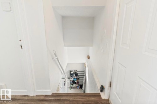 Staircase with wood-finish flooring and white painted walls - 12150 47 Street Nw, Edmonton, AB - Indoor Photo Showing Other Room