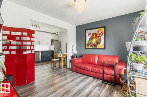Open-concept living area featuring wood-finish flooring, a contemporary chandelier, and a neutral color palette - 12150 47 Street Nw, Edmonton, AB - Indoor Photo Showing Living Room