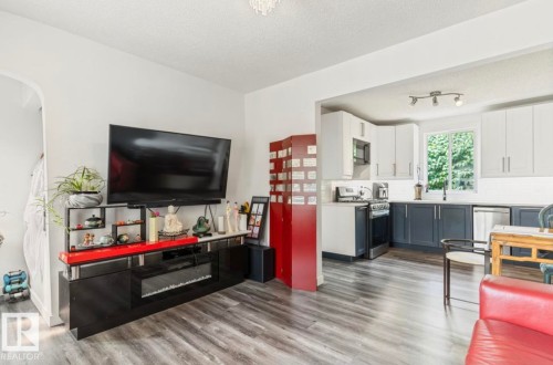 Open-concept living area with wood-finish flooring extending into the kitchen - 12150 47 Street Nw, Edmonton, AB - Indoor