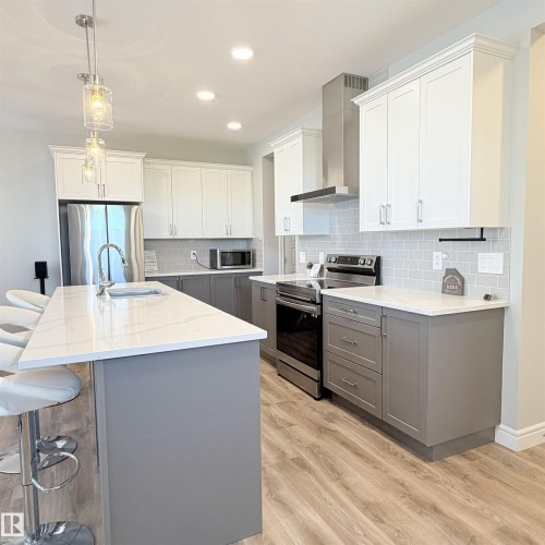 Kitchen featuring a center island, wood-finish flooring, recessed lighting, two-tone cabinetry, and a subway tile backsplash - 1003 Goldfinch Way Nw, Edmonton, AB 