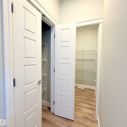 Two paneled interior doors, wood-finish flooring, and wire shelving units - 1003 Goldfinch Way Nw, Edmonton, AB 