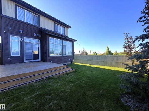 Expansive backyard featuring a new wooden deck with steps, a full privacy fence, and a sliding glass door for outdoor access - 1003 Goldfinch Way Nw, Edmonton, AB 