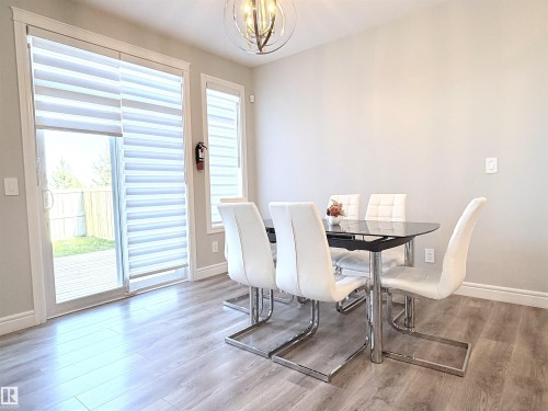 Wood-finish flooring, sliding glass door, white trim, and a modern ceiling fixture - 1003 Goldfinch Way Nw, Edmonton, AB 