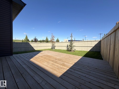 Expansive wooden deck with a grassy yard, surrounded by a wood-panel fence - 1003 Goldfinch Way Nw, Edmonton, AB 