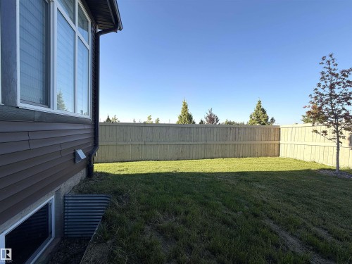 Expansive backyard featuring a manicured lawn, full perimeter privacy fencing, and a mature tree - 1003 Goldfinch Way Nw, Edmonton, AB 
