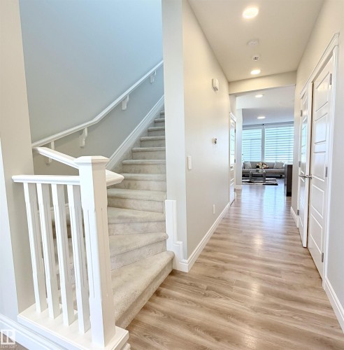 Hardwood-finish flooring, recessed lighting, white panel doors, and a carpeted staircase with white railings - 1003 Goldfinch Way Nw, Edmonton, AB 