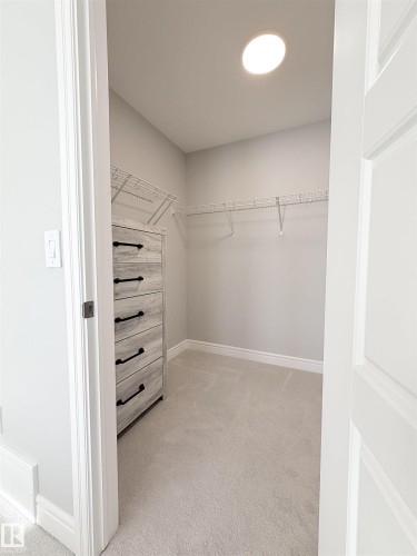Recessed ceiling light, wall-mounted wire shelving, built-in dresser with dark hardware, light gray carpet, and white trim - 1003 Goldfinch Way Nw, Edmonton, AB 