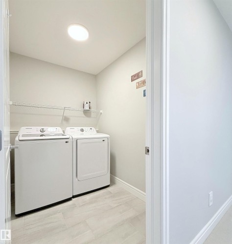 Laundry room featuring a wire storage shelf, overhead lighting, and light-toned tile flooring - 1003 Goldfinch Way Nw, Edmonton, AB 