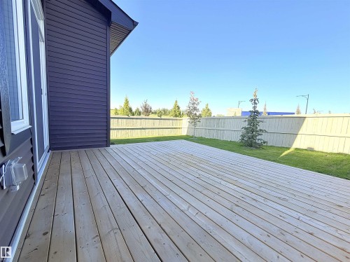 Expansive wood deck with a privacy fence, manicured lawn, and mature trees - 1003 Goldfinch Way Nw, Edmonton, AB 