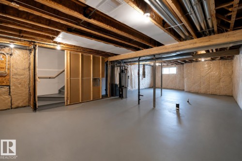 Spacious unfinished basement featuring exposed ceiling joists, insulated walls, and a painted concrete floor - 1003 Goldfinch Way Nw, Edmonton, AB 
