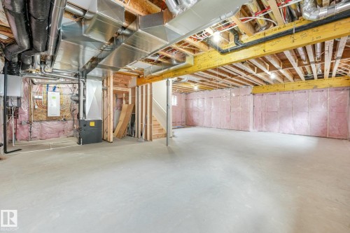 Unfinished basement featuring concrete flooring, exposed ceiling joists, wall insulation, and a visible staircase - 16 Middleton Close, Leduc, AB 