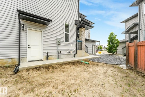 Gray siding exterior with a white door, black awning, and concrete walkway - 16 Middleton Close, Leduc, AB 