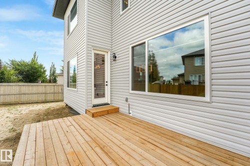 Spacious wood deck with a clear-paneled glass door, large window, and light-colored siding - 16 Middleton Close, Leduc, AB 