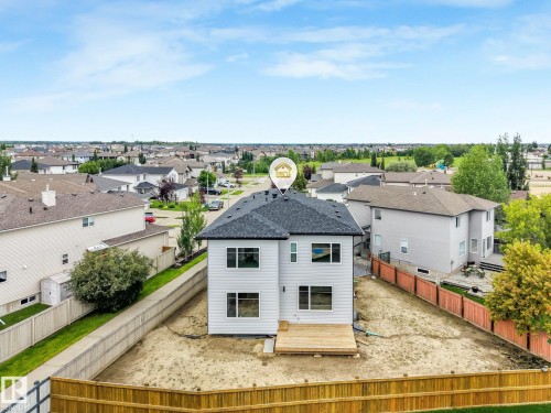 Contemporary two-story residence featuring a dark shingle roof, light-toned siding, a rear wooden deck, and multiple windows - 16 Middleton Close, Leduc, AB 
