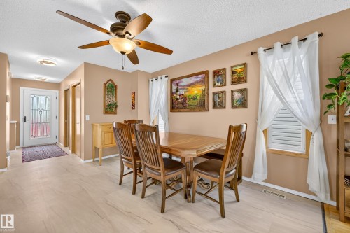 Spacious dining area featuring a ceiling fan with integrated lighting, wood-finish flooring, and natural light from the window - 1223 Gillespie Crescent Nw, Edmonton, AB 