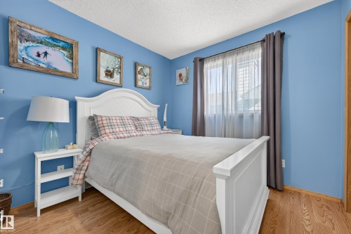 Wood-finish flooring, textured ceiling, and window with sheer and blackout curtains - 1223 Gillespie Crescent Nw, Edmonton, AB 
