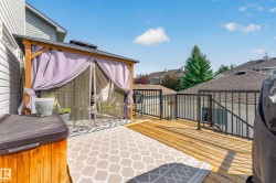 Wood-finish deck with black metal railings, featuring a covered gazebo - 