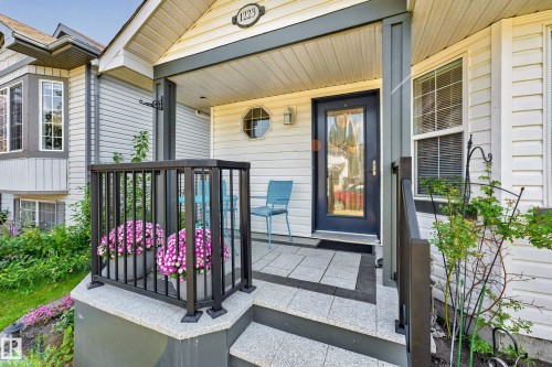 Covered entry with a dark-framed glass paneled door, bay window, white siding, and a decorative address plaque - 1223 Gillespie Crescent Nw, Edmonton, AB 
