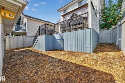 Raised outdoor deck with dark railing, blue-painted underdecking, and privacy curtains - 1223 Gillespie Crescent Nw, Edmonton, AB 