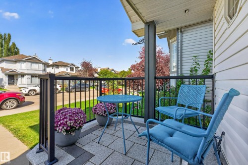 Covered front porch featuring a dark railing, stone tile flooring, and siding exterior - 1223 Gillespie Crescent Nw, Edmonton, AB 