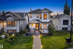 White siding exterior with dark trim accents, bay window, covered front porch, and established landscaping - 