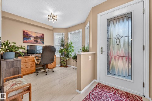 Entryway with a decorative glass front door, light wood-finish flooring, multiple windows, and a semi-flush mount ceiling light - 1223 Gillespie Crescent Nw, Edmonton, AB 