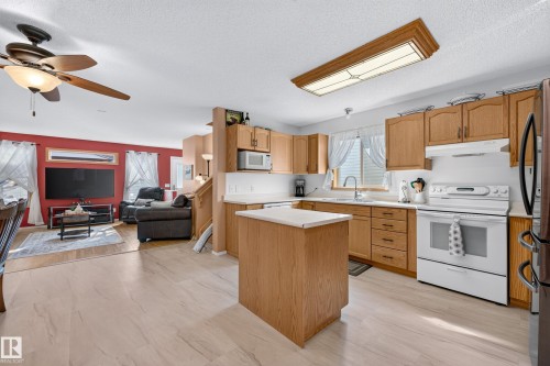 Kitchen with wood-finish cabinetry, white appliances, and a central island - 1223 Gillespie Crescent Nw, Edmonton, AB 