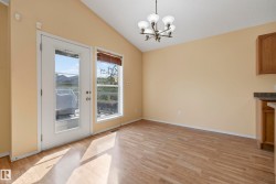 Vaulted ceiling with a multi-light chandelier, wood-finish flooring, and a glass-paneled door - 