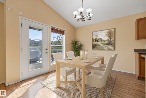 Vaulted ceiling, wood-finish flooring, glass-paneled door, pendant lighting fixture, and window with blinds - 15213 49A Street Nw, Edmonton, AB 