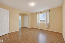 Wood-finish flooring, neutral wall tones, arched doorway, bi-fold closet doors, and recessed window - 
