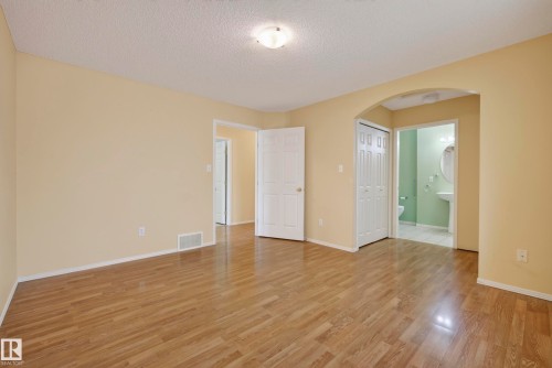 Wood-finish flooring, neutral wall tones, arched doorway, bifold closet doors, and recessed lighting - 15213 49A Street Nw, Edmonton, AB 