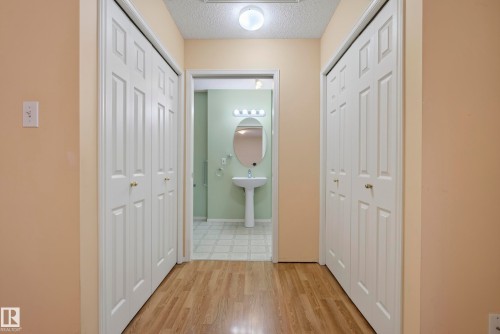 Hallway featuring wood-finish flooring and bi-fold panel doors - 15213 49A Street Nw, Edmonton, AB 
