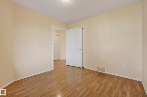 Wood-finish flooring throughout, neutral wall paint, and white trim - 15213 49A Street Nw, Edmonton, AB 