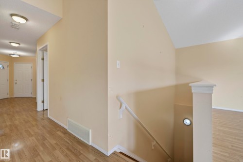 Wood-finish flooring throughout, vaulted ceiling, white trim, and a built-in stairwell light - 15213 49A Street Nw, Edmonton, AB 