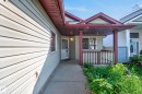 Light-colored horizontal siding exterior with a covered porch featuring a white railing and dark trim - 15213 49A Street Nw, Edmonton, AB 