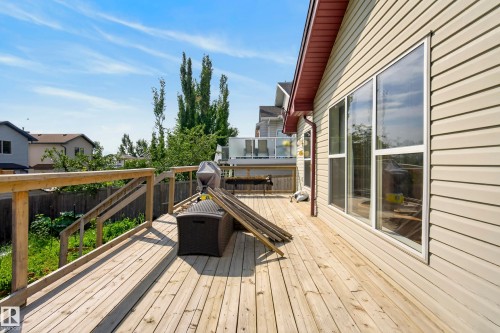 Expansive wood deck with wood railings, featuring a vinyl siding exterior and large windows - 15213 49A Street Nw, Edmonton, AB 