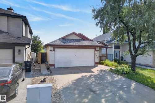 Siding exterior with a gable roof, integrated garage, concrete driveway, and mature landscaping - 15213 49A Street Nw, Edmonton, AB 