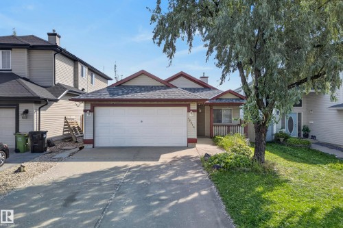 Attached two-car garage, front porch with white railings, and mature front yard tree - 15213 49A Street Nw, Edmonton, AB 