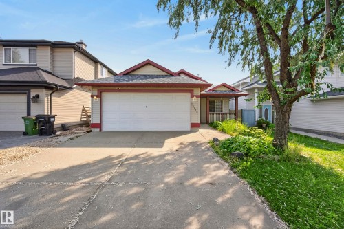 Attached front-entry garage with a concrete driveway, covered porch with wood railing, and shingle roofing - 15213 49A Street Nw, Edmonton, AB 