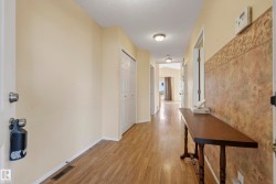 Hallway featuring wood-finish flooring, neutral wall tones, and recessed lighting - 