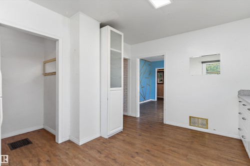 Wood-finish flooring, white walls, built-in cabinetry with glass panels, and recessed ceiling lighting - 5501 48 Avenue, Wetaskiwin, AB 