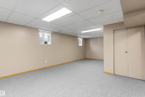 Finished lower level featuring neutral carpeting, two windows, recessed lighting, and a closet with bifold doors - 5501 48 Avenue, Wetaskiwin, AB 