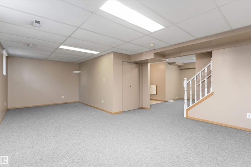 Expansive carpeted area with neutral wall tones and a drop ceiling - 5501 48 Avenue, Wetaskiwin, AB 